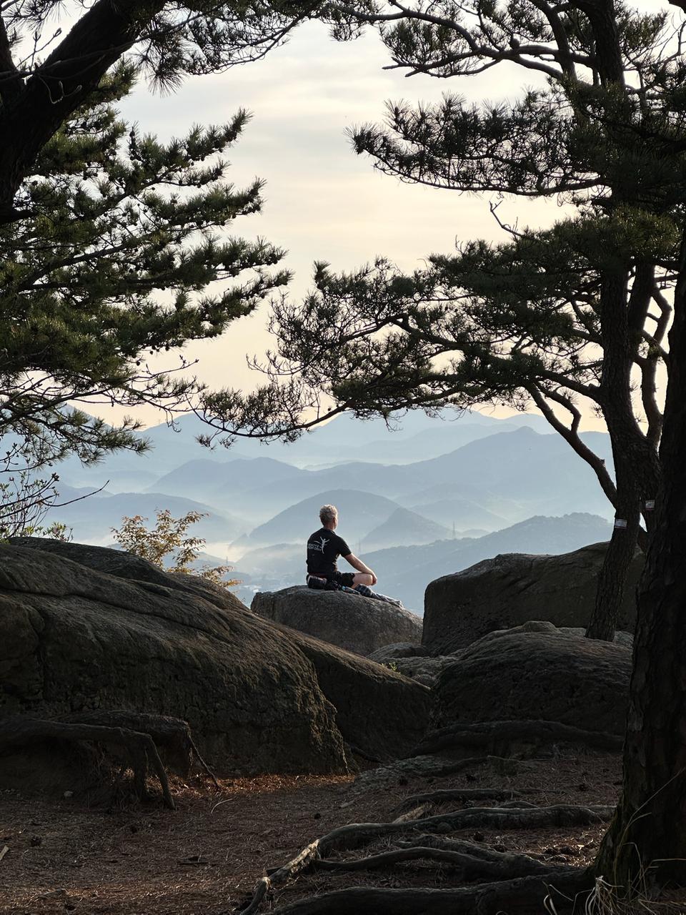 Benoit Foucher sitting quietly on a rock above misty mountains